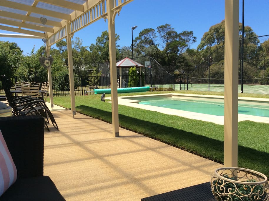View from Bungalow verandah across lawn to heated pool and tennis court.