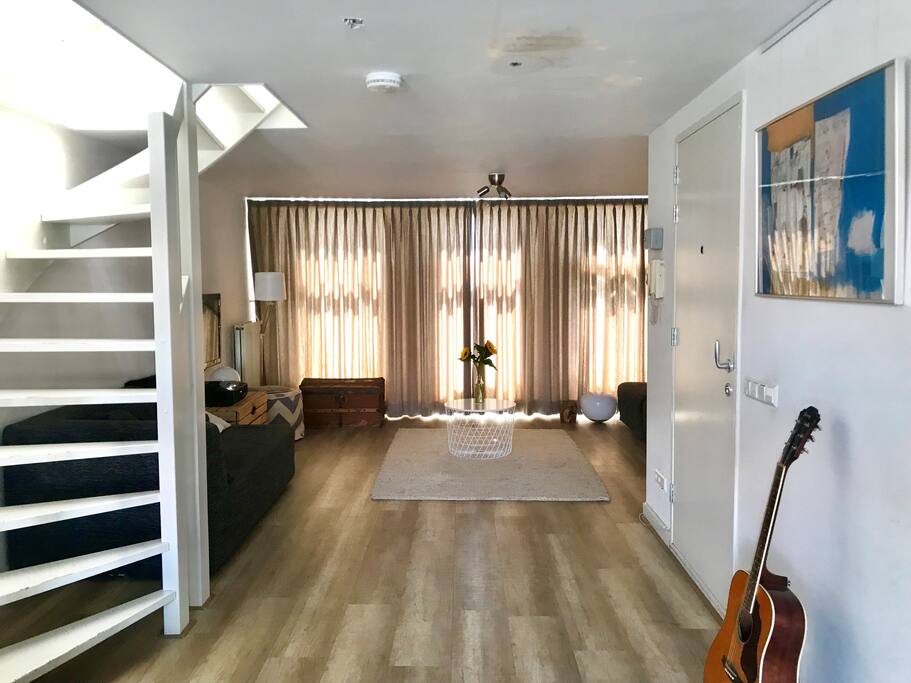 Bright living area, lazy couch, windows on both sides of this floor of the appartment, tv, toilet and also a place for the kids to play.