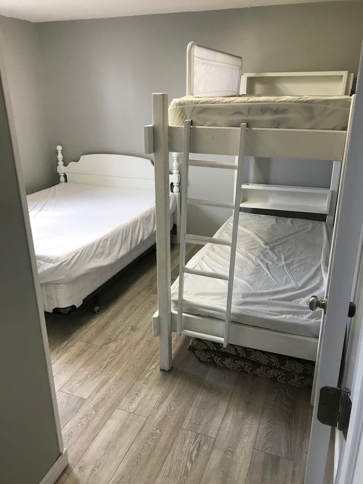 Dormitorio en la planta baja con literas individuales y cama tamaño queen. 