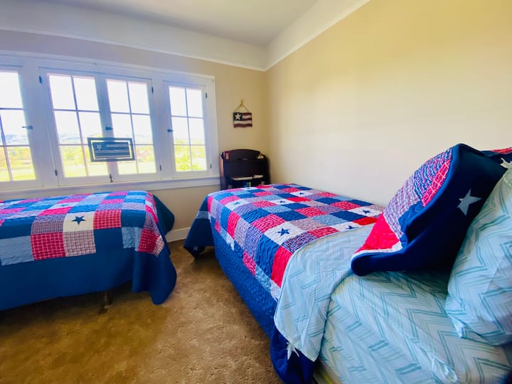 سريران بحجم مزدوج مع نوافذ تفتح على مناظر طبيعية ريفية جميلة. 