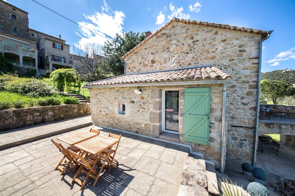 Appréciez les repas ou la détente sur la grande terrasse, équipée d'une table et de quatre chaises. La porte vitrée donne directement sur la cuisine, et l'escalier à droite mène à l'espace jardin.