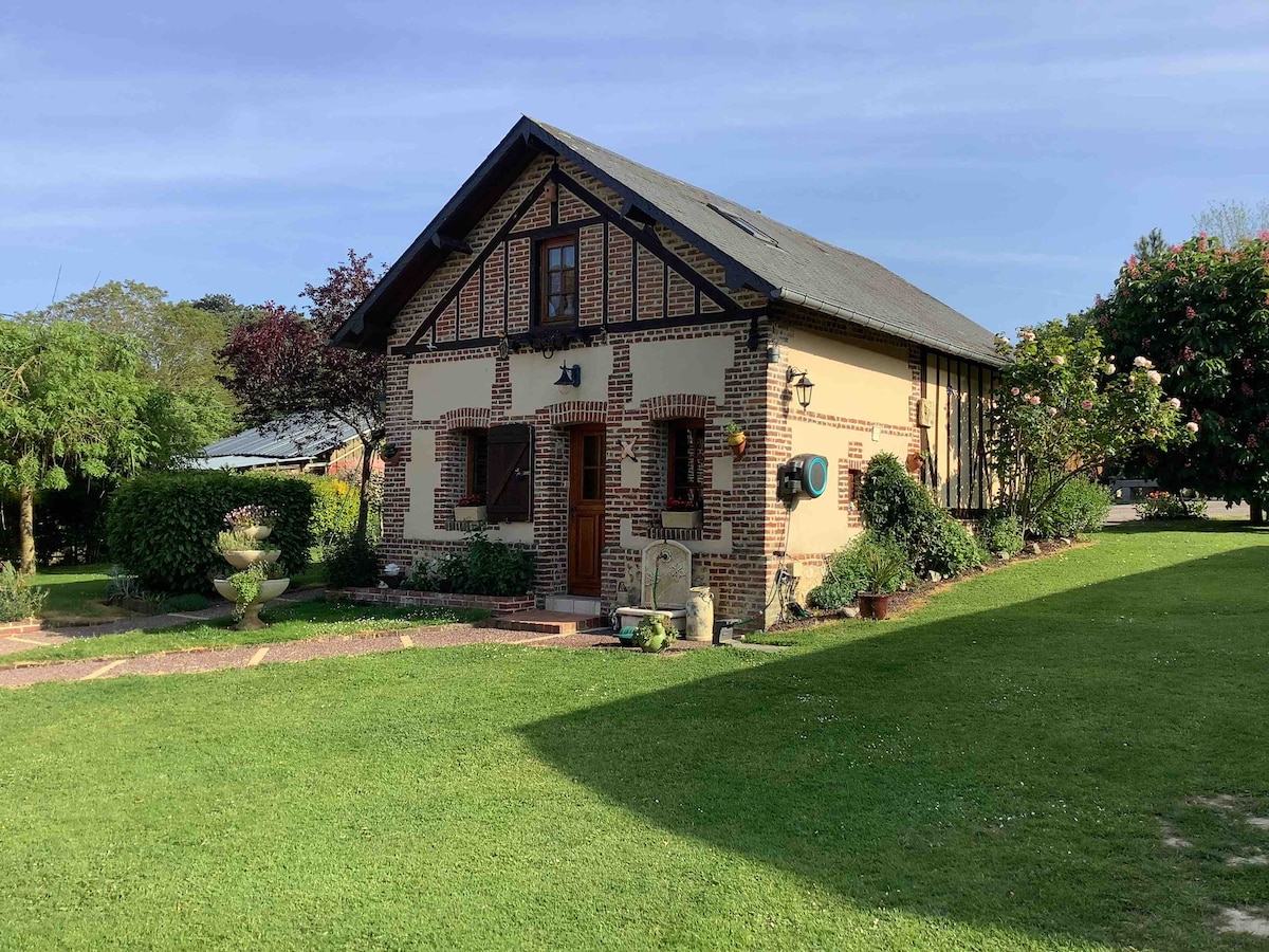 A charming two-story country house features a blend of brick and wooden elements. Lush greenery surrounds the property, complemented by manicured lawns and flower beds. Open areas invite relaxation, while the well-maintained exterior suggests a welcoming ambiance.
