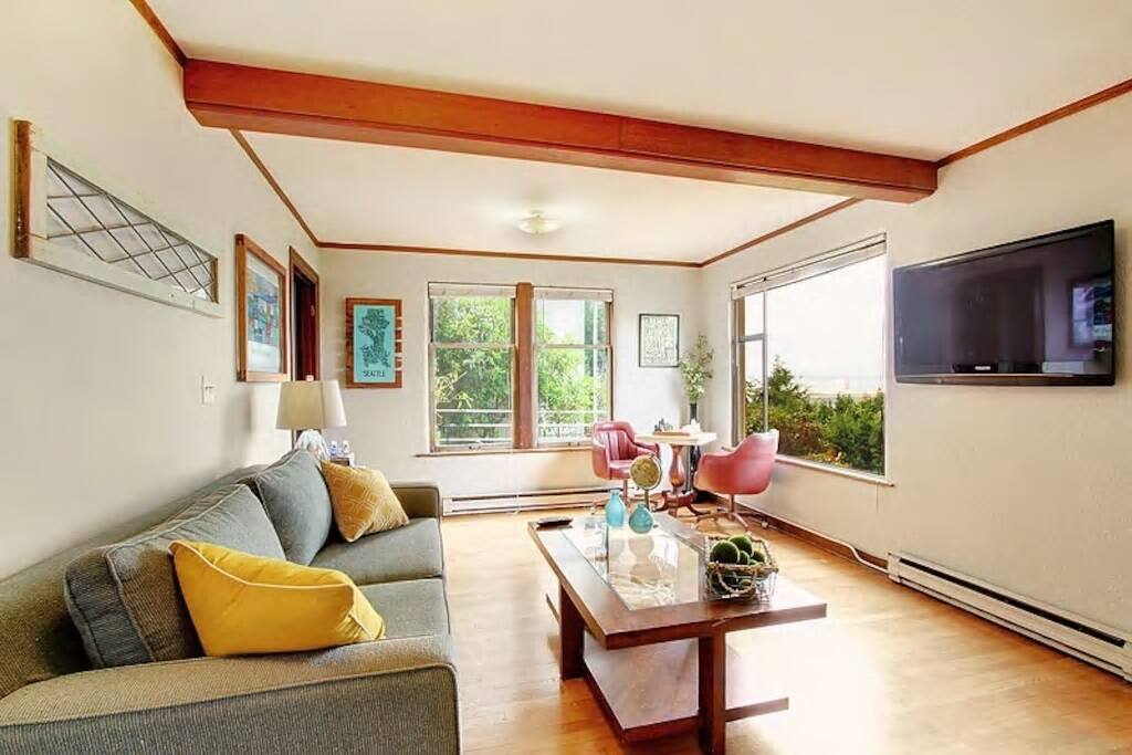 Large view living room w/ hardwoods, mahogany trim, built-in, fun artwork & furnishings!