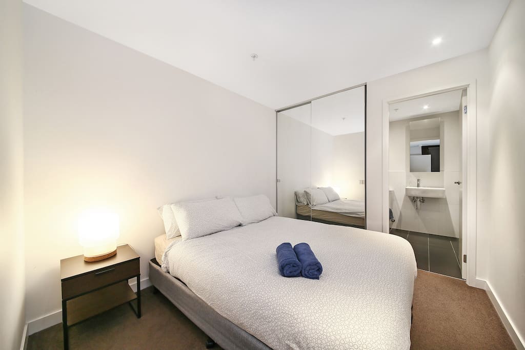 A bedroom with a queen sized bed & plush pillows.