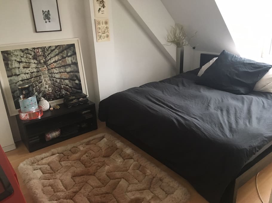 Room with king bed, pillows and bed sheets. View to the outside.