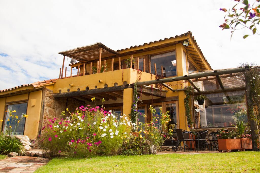 Fachada y pérgola con mesitas