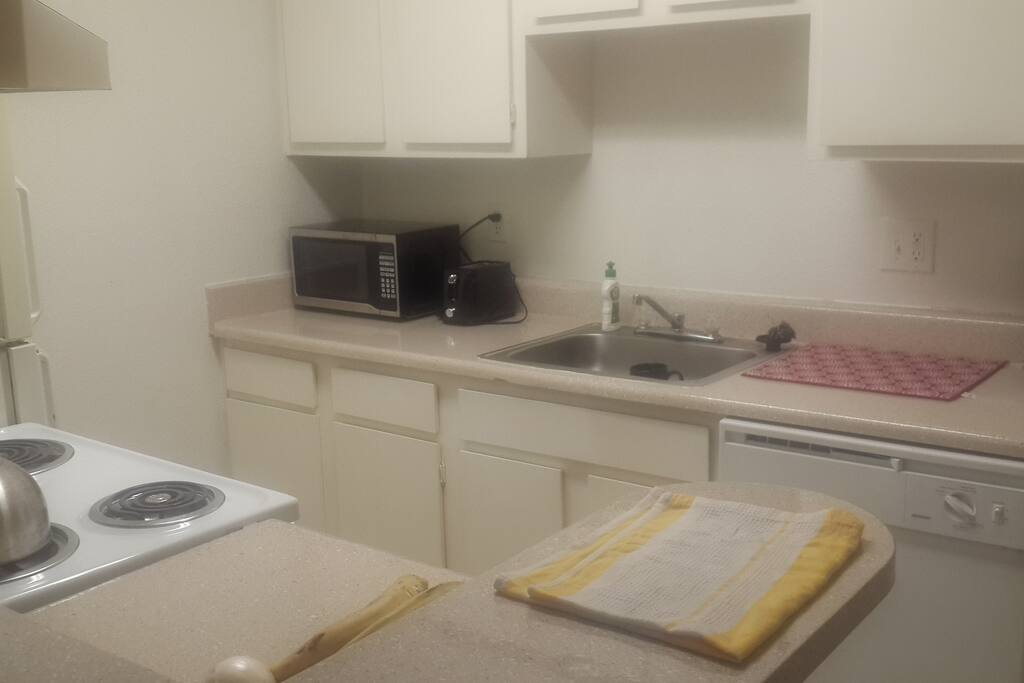 Kitchen with stove, refrigerator, coffee maker, microwave, toaster and cooking utensils.
