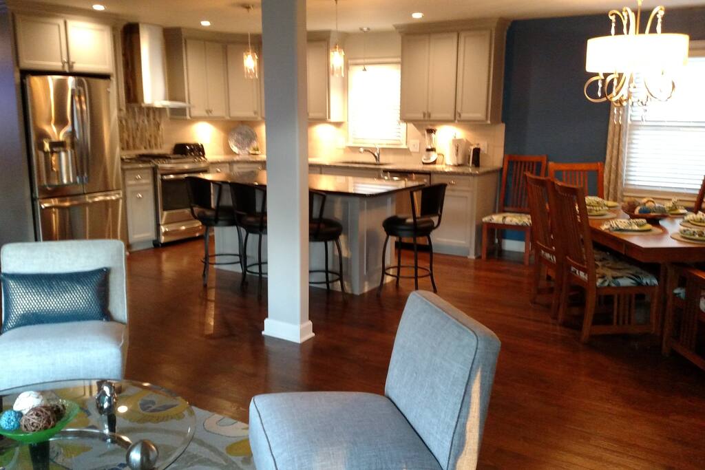 View of kitchen and kitchen island with granite countertops. Partial view of dining room right next to the kitchen and living room seating area when you walk in the front door.