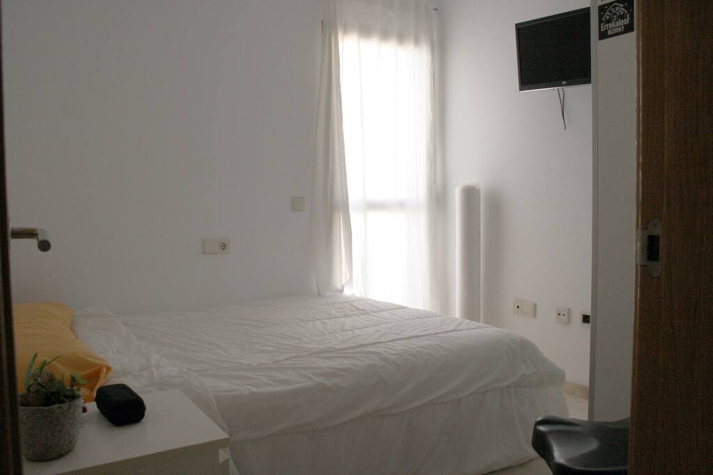 Habitación de unos 8 m2 con cama de matrimonio, con armario, TV y pequeña terraza privada.
Room of about 8 m2 with double bed, with wardrobe, TV and small private terrace.