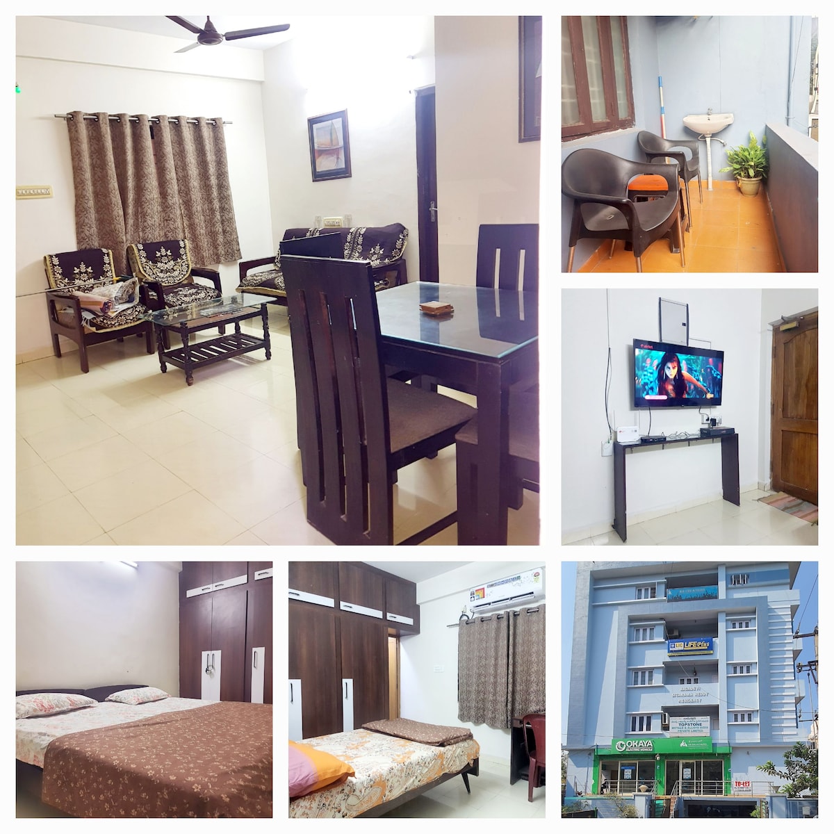 A spacious living area contains a wooden dining table and comfortable seating. A television is mounted on the wall, with decorative curtains framing the windows. Bedrooms display double and queen beds with soft linens. The building exterior includes accessible entry and nearby amenities.