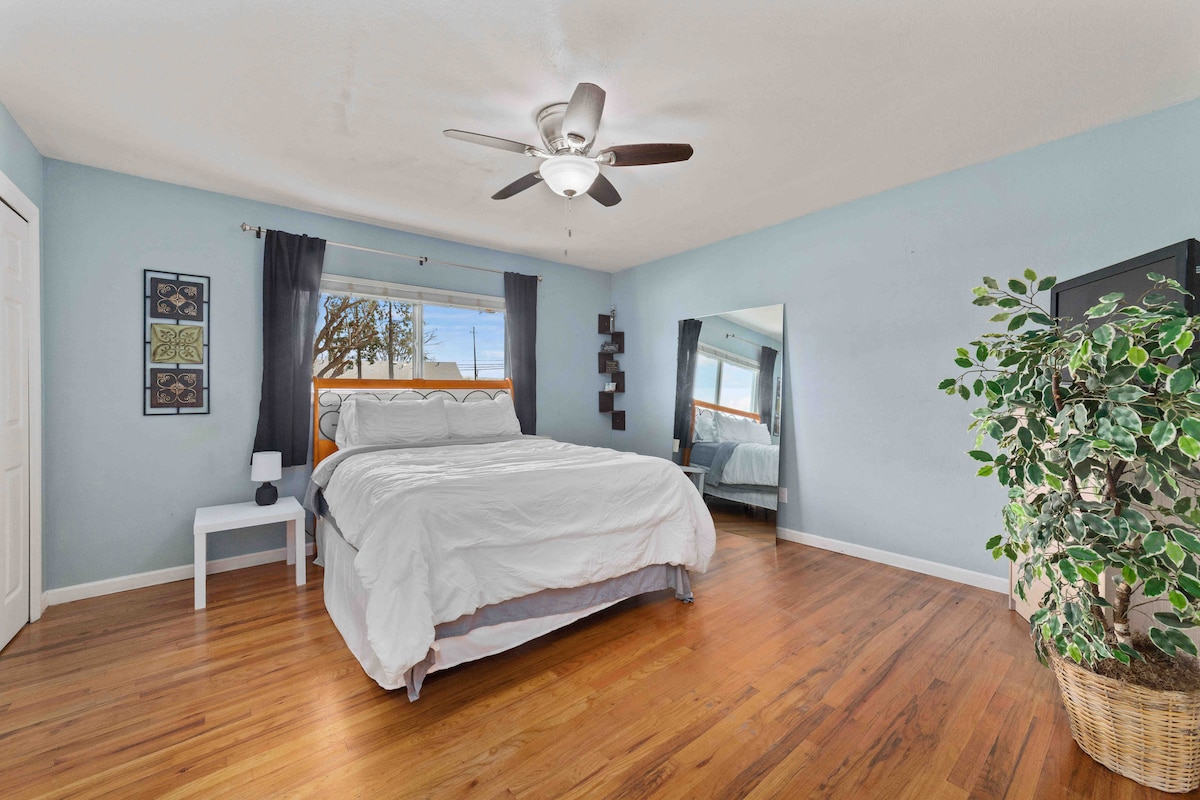 Plava soba ima jedan bračni krevet, noćne ormariće, TV, veliko ogledalo i ormar. Kroz prozor se pruža pogled na prednje dvorište/prednje parkiralište.