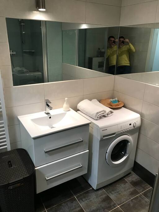 Bathroom with washing machine, shower, toilet, foen, towels, shampoo
