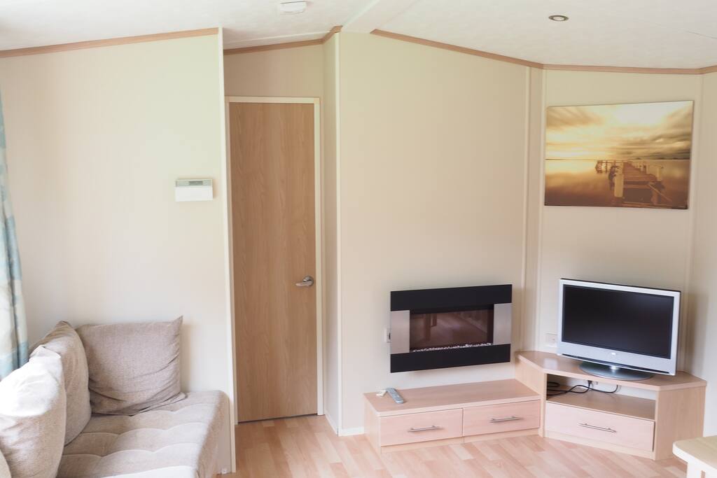 Ruime woonkamer,met grote bank, tafel met 4 stoelen, kabel-tv en sfeer haard.