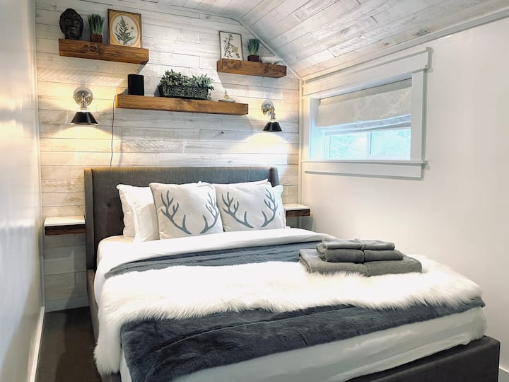 Cozy Bedroom with premium bedding & accessories, Edison Bulb sconces, blackout window shades, & barn wood accent wall & vaulted ceilings. Sonos WIFI speaker with Wall mounted 42'' flat screen smart TV.