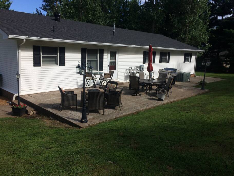 Large concrete patio at back of house with natural gas firepit and grill