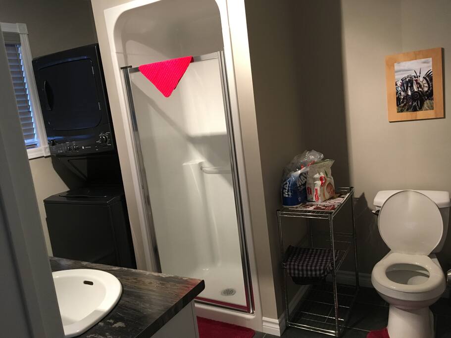 Salle de bain complète incluant laveuse-sécheuse superposées.