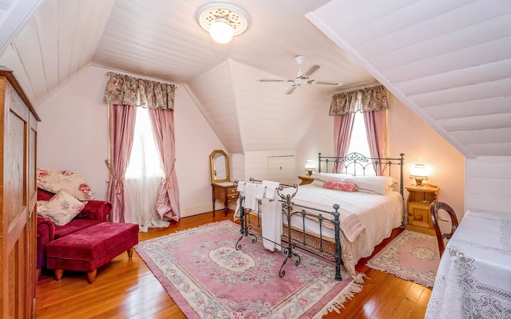 Second attic bedroom with queen size iron bed, wool rugs and pink silk curtains