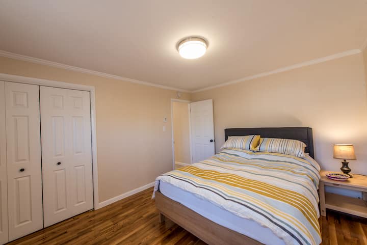 חדר שינה עם מיטת קווין סייז, ארון מרווח, דלת למרפסת עץ, תריסים שחורים