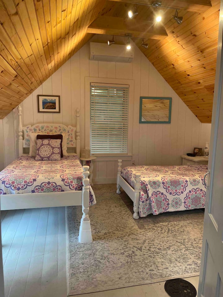 Back bedroom with two twin beds. 5 drawer dresser and large closet with hanging space not pictured. Heat/AC split added above visible window in 2022. With upstairs door closed, it keeps the entire upstairs fairly cool (this bedroom is coldest).