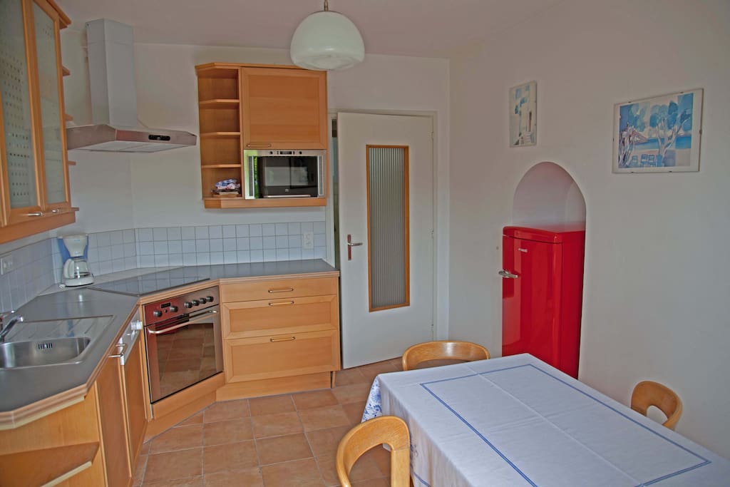 Küche mit Geschirrspühler, Backofen und Mikrowelle; Zugang zur Terasse