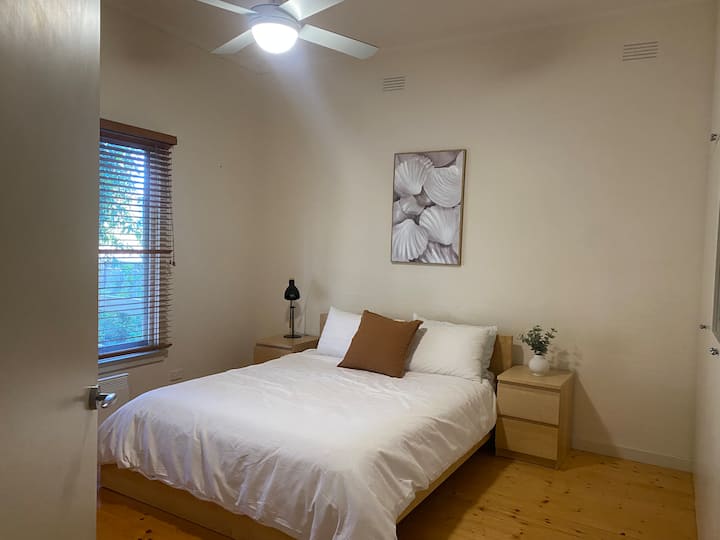 Საძინებელი 2 - გადაჰყურებს წინა ბაღს. Წარმოდგენილია დედოფლის ზომის საწოლი, დიდი კარადები ნივთების შესანახად, ელექტრო პანელური გამათბობელი და პორტატული ვენტილატორი.