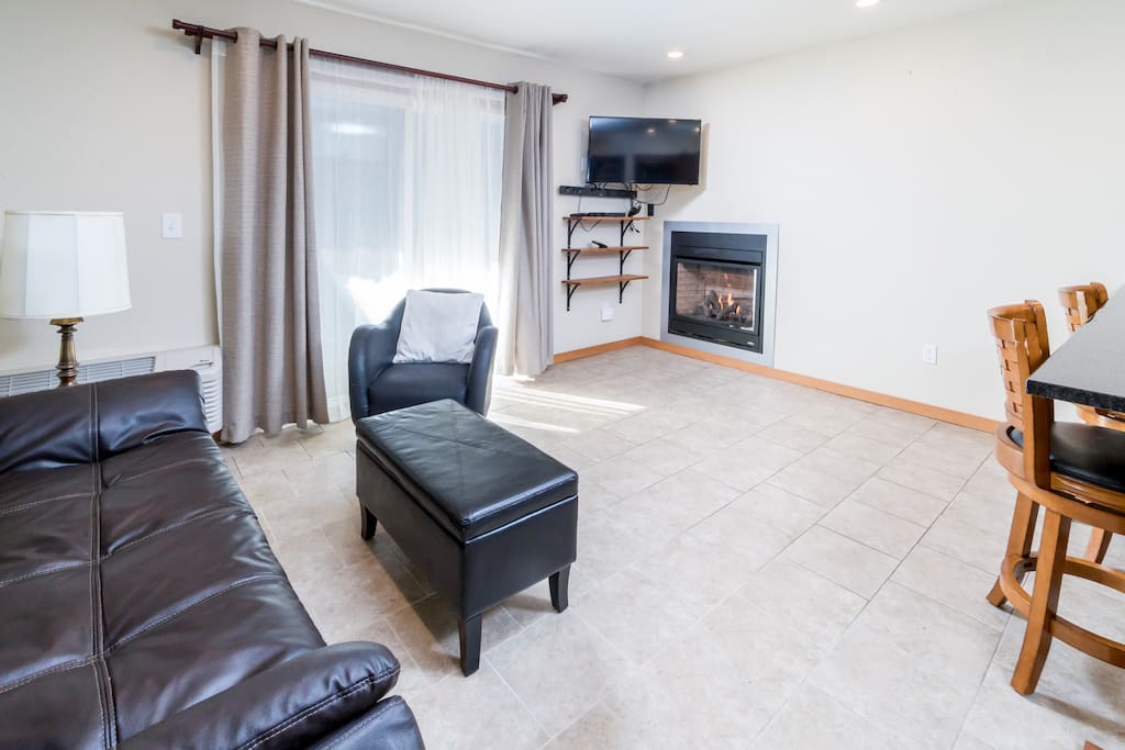 Living area with 3-seat leather sleeper sofa, warm gas fireplace, and flat screen TV.