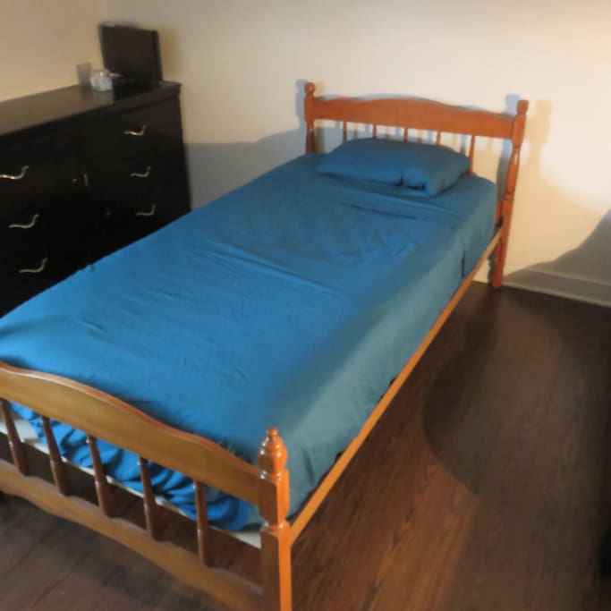 chambre à lit simple avec un bureau un commode et une penderie.
