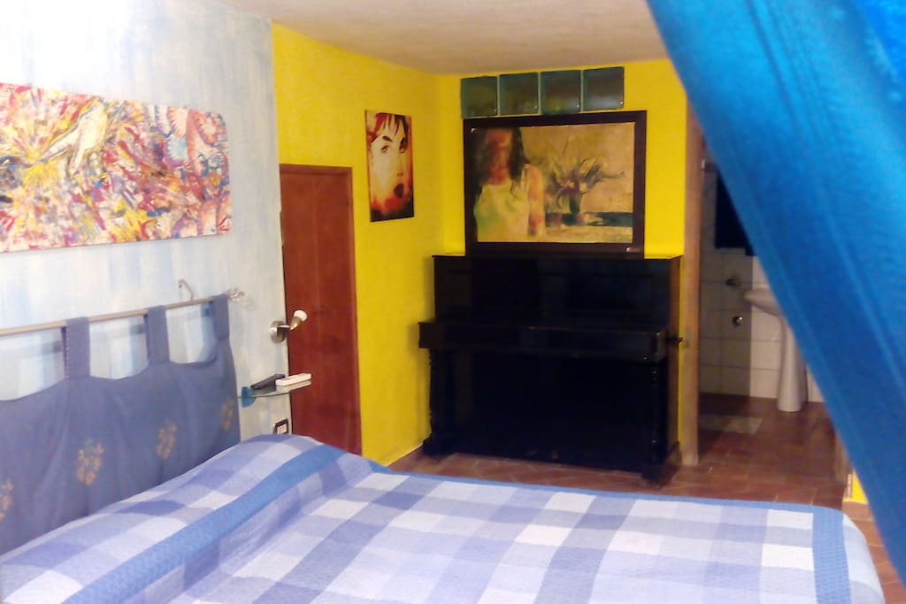 camera da letto con pianoforte e zona bagno in camera