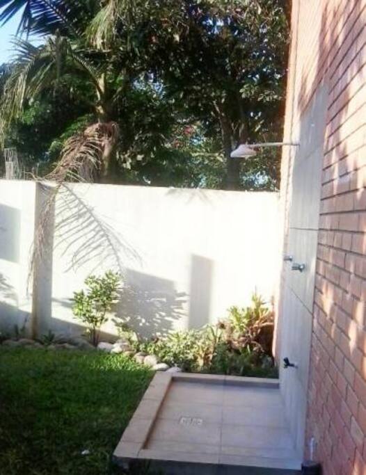 Jardim Frontal da esquerda com chuveirinho para tirar a areia da praia e a noite estacionamento para um veículo.