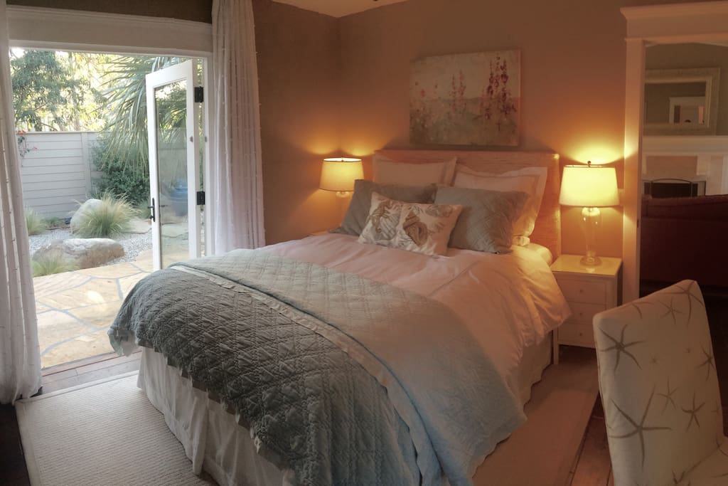 Cozy clean bedroom with very comfortable queen bed, dressing table, armoire, walk-in closet, en-suite bathroom, and French doors opening to private garden and eating area with private outdoor shower.