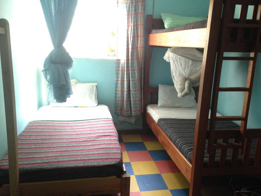 One of our dorm rooms containing three beds (all with mosquito nets) and wardrobe.