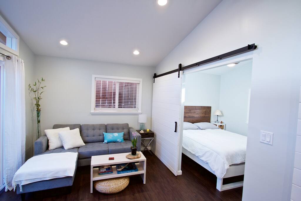 View of living room and bedroom with large sliding barn door for privacy.