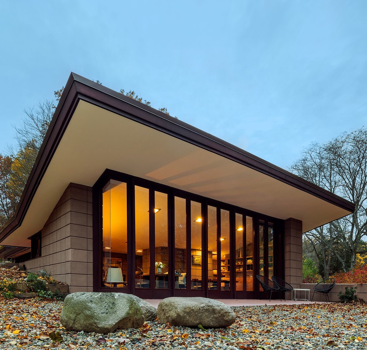 Una casa increíble de ladrillo diseñada por Frank Lloyd Wright, ubicada en un entorno natural con ventanas del piso al techo que cubren todo un costado.