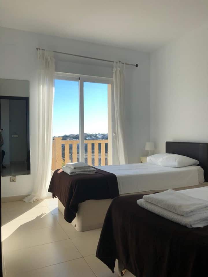 หนึ่งในสองห้องนอนแฝดที่มองออกไปเหนือระเบียงและมีวิวทะเลและภูเขาและเข้าถึงสระว่ายน้ำได้  ห้องนอนเตียงคู่อีกห้องเหมือนกันแต่ตั้งอยู่ฝั่งตรงข้ามของทางเดินเพื่อเริ่มต้นวันที่เงียบสงบขึ้น!