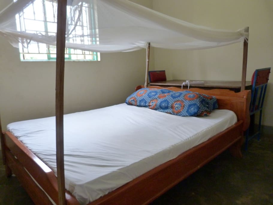 Bed with office desk behind it (mosquito net above).