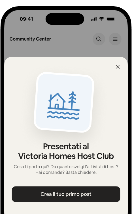 Telefono che mostra la scheda di benvenuto "Presentati al Victoria Homes Host Club" con un pulsante "Crea il tuo primo post".