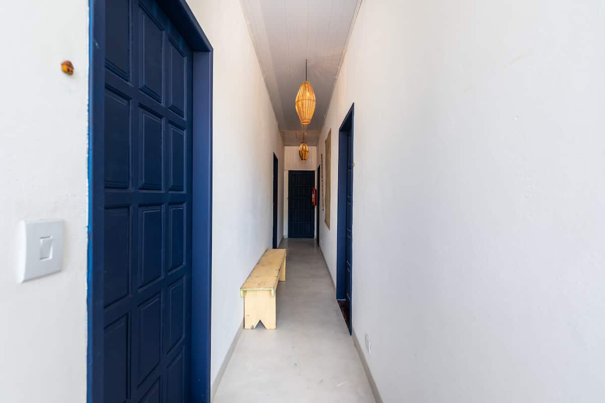 Corredor interno da Casa Maruê com as portas azuis das suítes