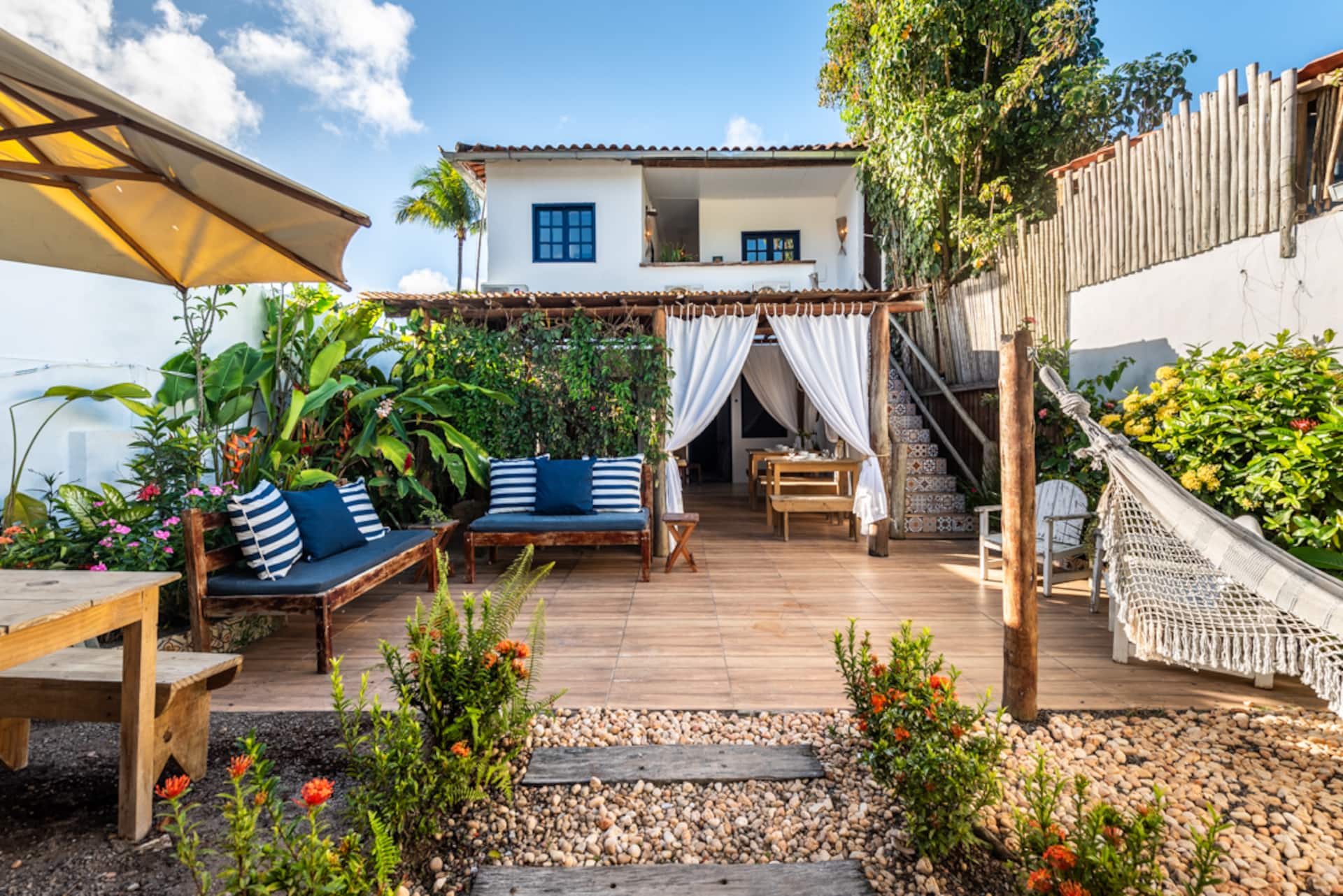 Deck da Casa Maruê com pergolado, rede e jardim