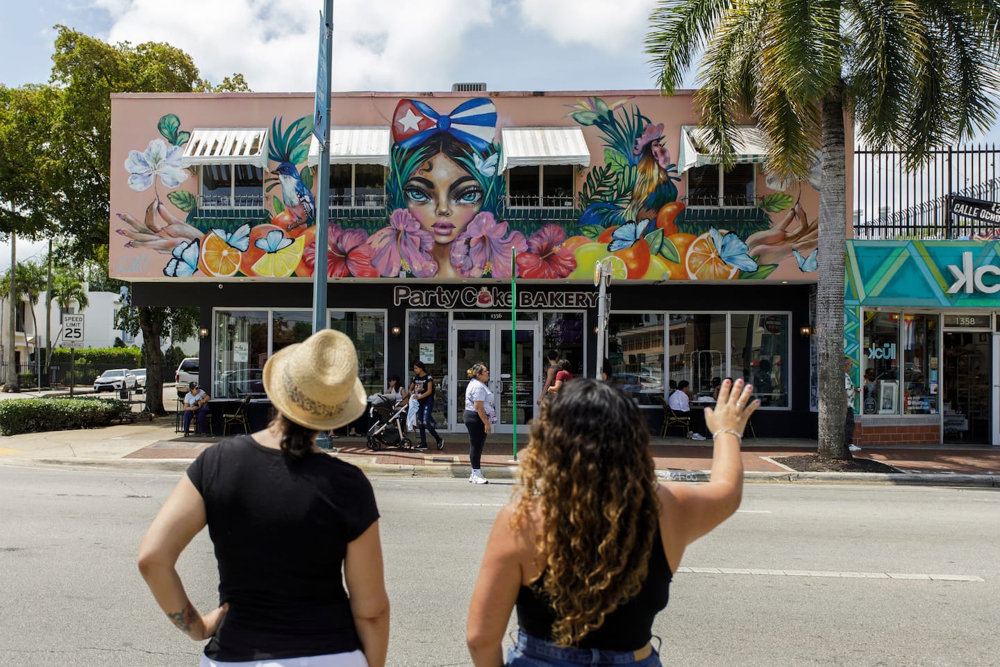 Didi pointing out a large tropical mural above Party Cake Bakery on Calle Ocho in Little Havana