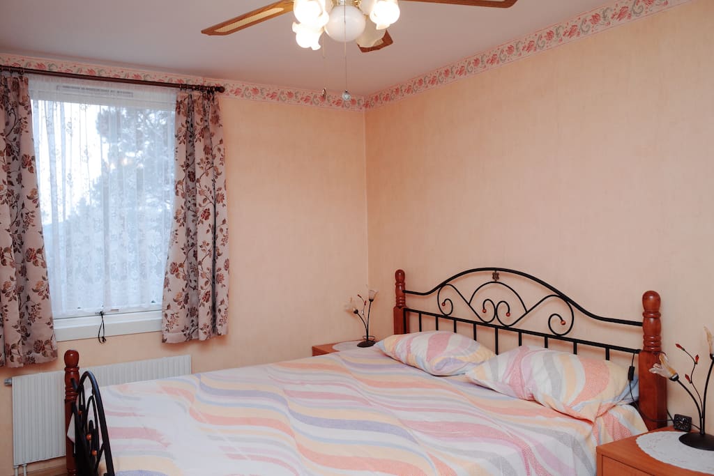 Your bedroom with a queen bed, ceiling fan and desk.