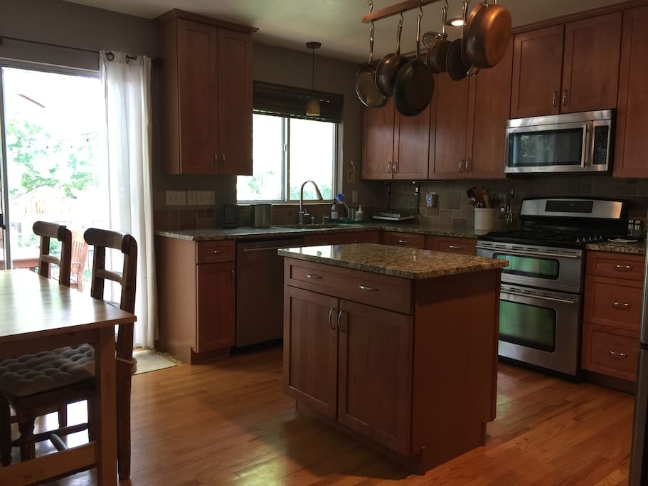 Eat-in kitchen with extendable table, granite countertops, and stainless steel appliances. Sliding glass doors access the deck and backyard.