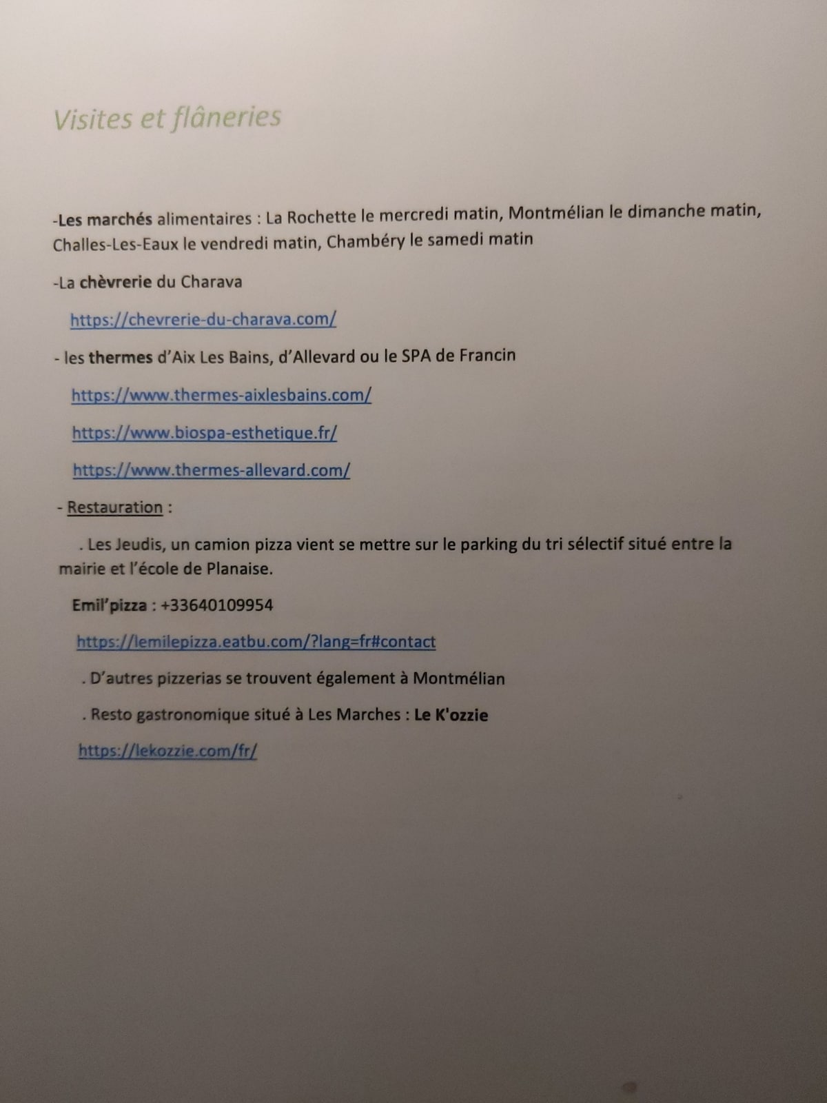 A printed list of local markets and restaurant options is displayed. The text outlines various days and locations for farmers' markets, and includes addresses for nearby services such as a pizzeria and a spa, providing useful information for visitors.