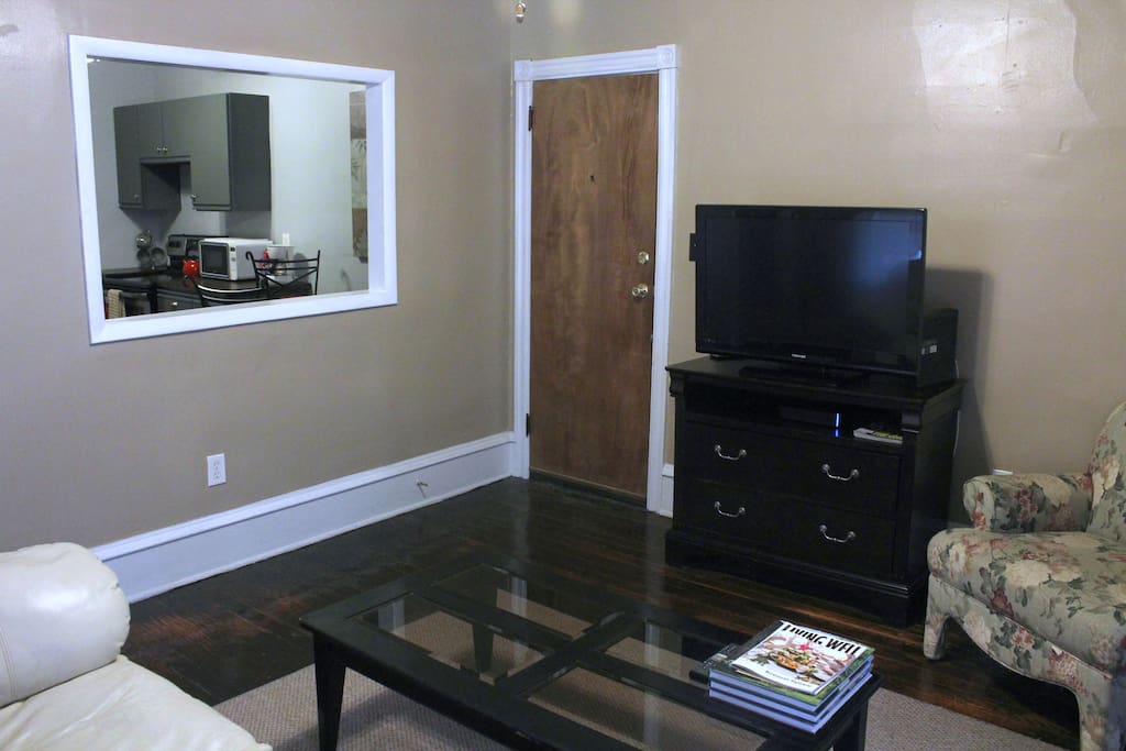 Bright living room offers oversized windows with shades, leather couch, 37" flat screen tv, comfortable chair.