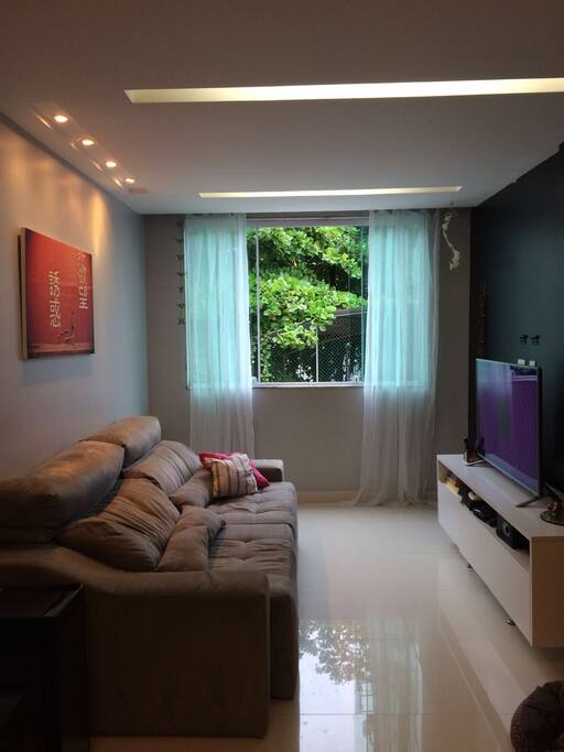 Sala de estar com sofá, smart TV e vista para a Pedra da Gávea