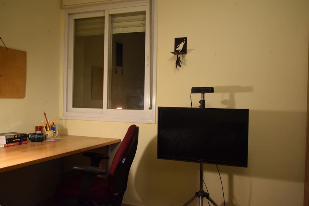 A desk with perfect light next to the window and a flat screen.