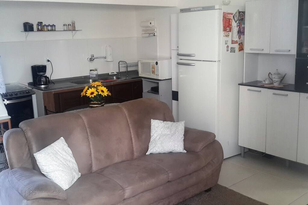 Cozinha americana com geladeira, fogão, cafeteira, microondas e todos utensílios domésticos.
