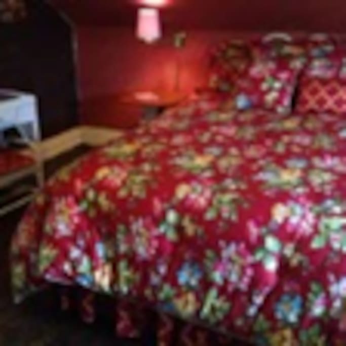 Red bedroom is cozy and private with its own footed tub and commode cubicle; lavatory and wicker furnishings as well as cornices from old house that burned that are made into bedside tables by local craftsman.