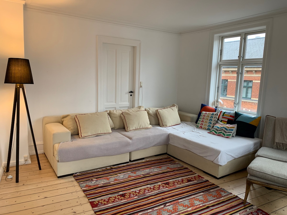 Woonkamer met bank die ruimte biedt voor maximaal twee personen die erop slapen. 