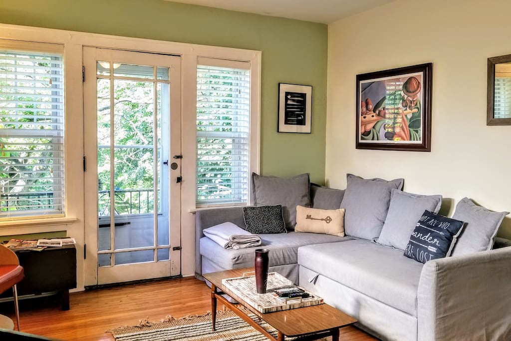 Living Room. One guest reported, "There is a welcoming front living room with a small balcony that looks out over the street. We enjoyed Netflix on the couch." :) We change some of our decor and furnishings seasonally, but we always keep this same layout.