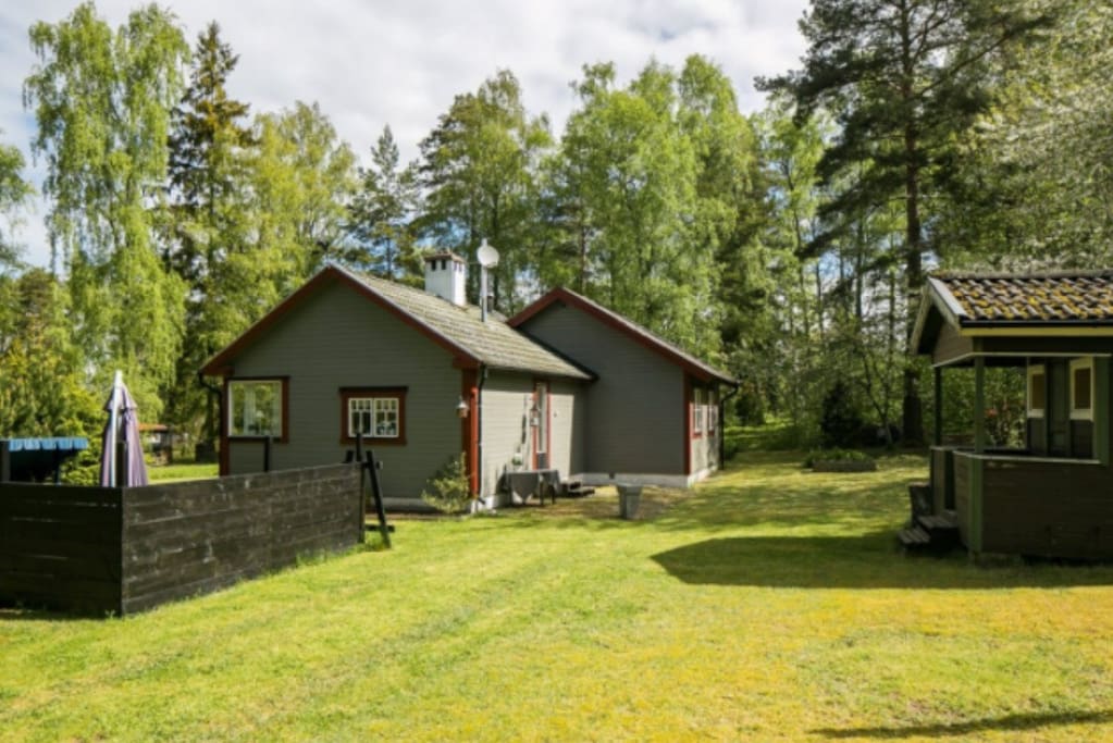Skyddad uteplats med eldstad och bodar på baksidan. På baksidan finns numera en nybyggd terrass.